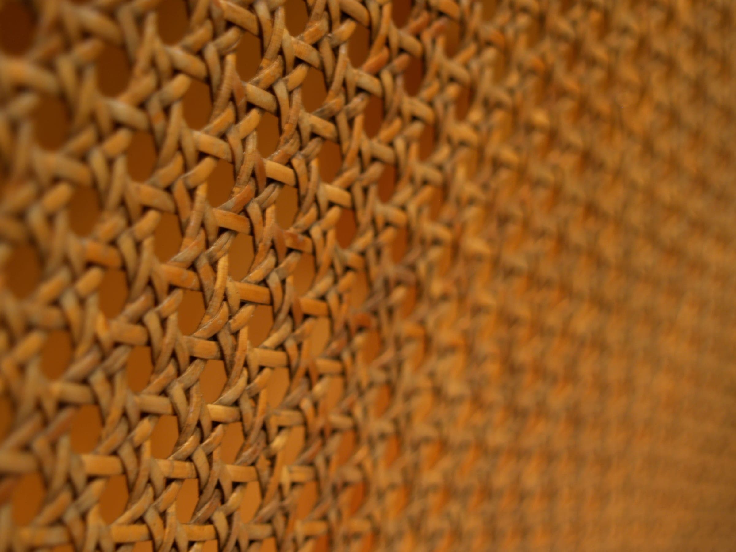 Woven cane in warm orange light, its pattern falling out of focus.